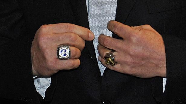 Die Hände eines Mannes mit Ringen an den Fingern, der einen Anzug trägt.