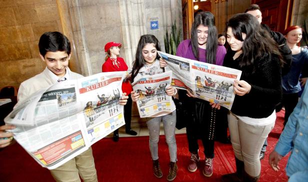 Eine Gruppe Jugendlicher liest die Zeitung „Kurier Extra“.
