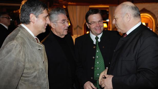 Vier Männer in Anzügen unterhalten sich angeregt.