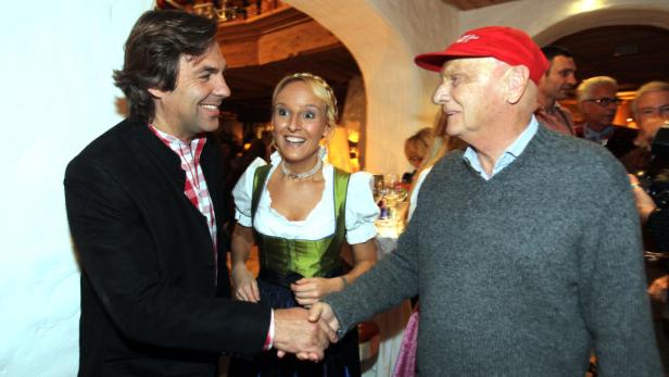 Zwei Männer schütteln sich die Hände, während eine Frau im Dirndl lächelt.