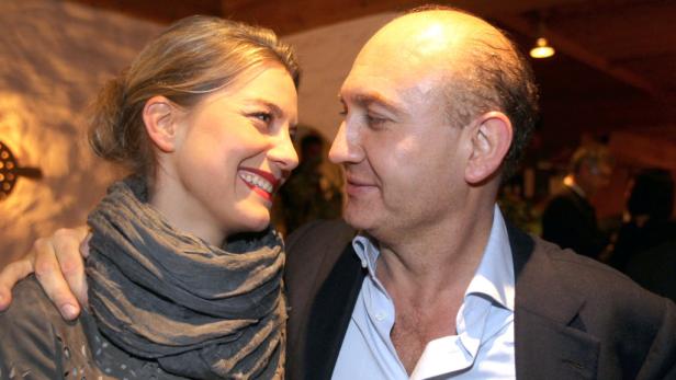 Eine lächelnde Frau mit grauem Schal und ein Mann sehen sich an.