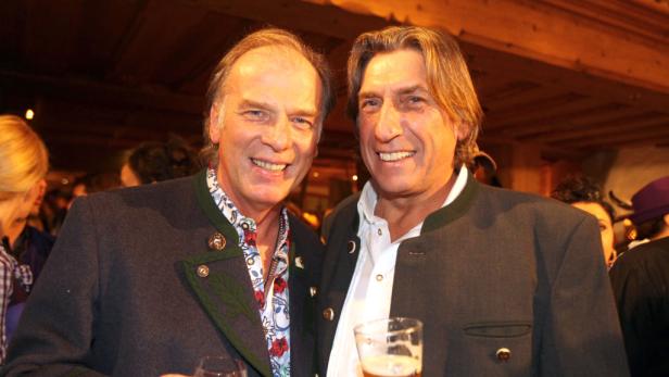 Zwei Männer in Trachtenjacken lächeln in die Kamera und halten Biergläser.