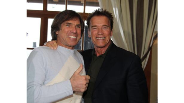 Arnold Schwarzenegger posiert mit einem Mann für ein Foto.