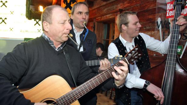 Drei Männer spielen traditionelle Musik mit Gitarre und Kontrabass, einer mit Mundharmonika.