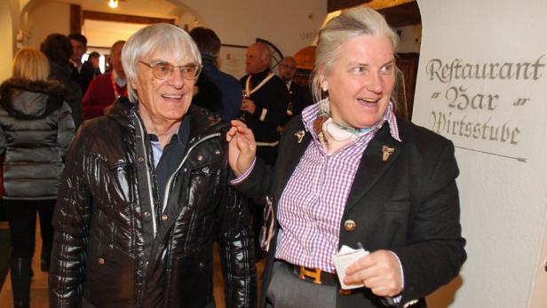 Bernie Ecclestone mit einer Frau vor dem Schild eines Restaurants.
