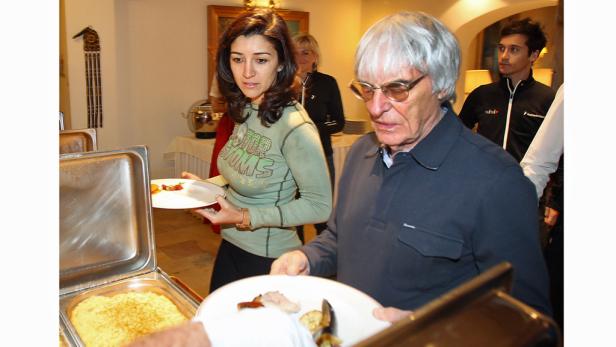 Bernie Ecclestone und eine Frau bedienen sich an einem Buffet.
