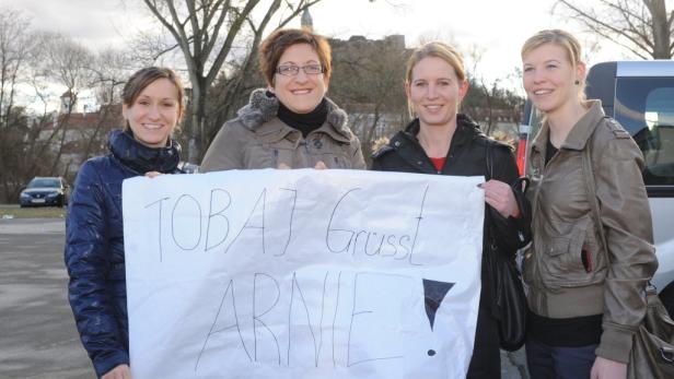 Vier Frauen halten ein Schild mit der Aufschrift „Tobaj Grüsst Arnie!“.