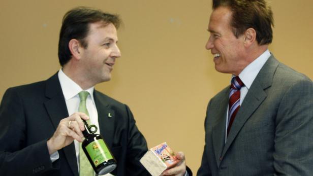 Arnold Schwarzenegger und ein Mann im Anzug halten steirische Produkte in den Händen.