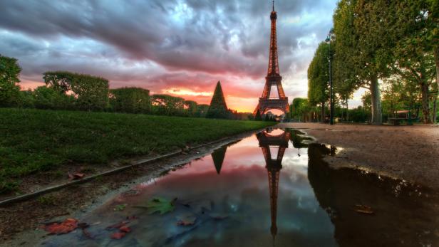 Der Eiffelturm spiegelt sich in einer Wasserpfütze im Park.