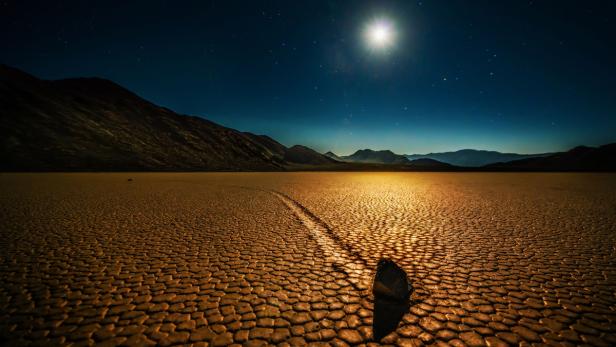 Ein Stein liegt auf der ausgetrockneten Ebene im Death Valley unter einem Sternenhimmel.