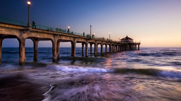 Eine Seebrücke erstreckt sich ins Meer, beleuchtet von Straßenlaternen.