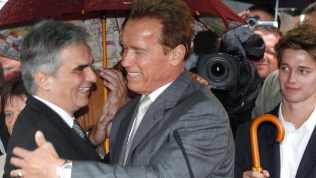 Arnold Schwarzenegger umarmt einen Mann bei einer Veranstaltung im Freien.