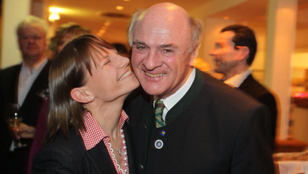 Eine junge Frau gibt einem älteren Mann im Trachtenanzug einen Kuss auf die Wange.