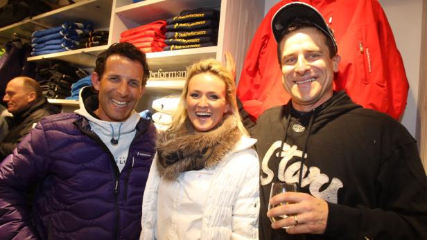 Drei Personen posieren lächelnd in einem Geschäft für Sportbekleidung.