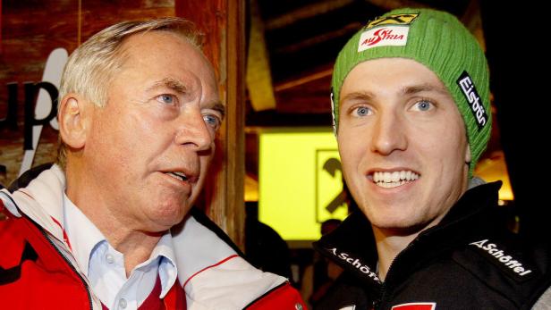 Ein älterer Mann und ein junger Mann mit grüner Mütze stehen nebeneinander.