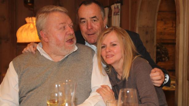 Drei Personen sitzen an einem Tisch und posieren für ein Foto.