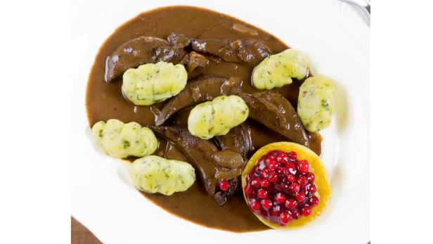 Ein Teller mit Leber, Gnocchi und Preiselbeeren in Sauce.