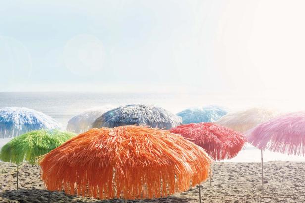 Mehrere bunte Sonnenschirme stehen am Strand.