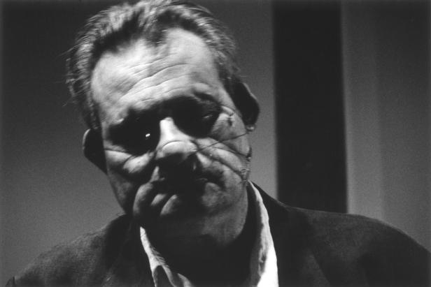 Ein Schwarzweißporträt eines Mannes mit markantem Gesichtsausdruck.