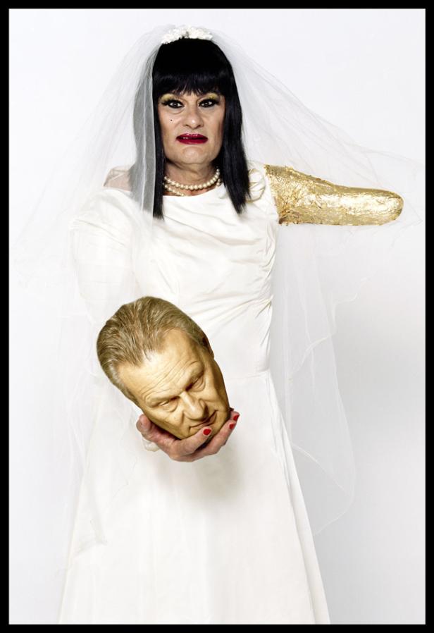 Eine Frau im Brautkleid hält einen abgetrennten Kopf in der Hand.