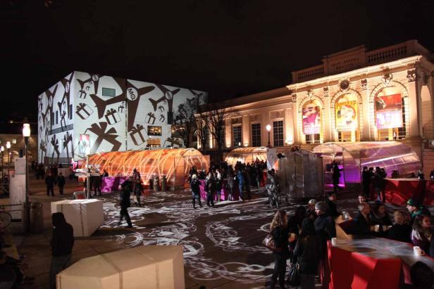 Das Museumsquartier in Wien ist nachts beleuchtet und von Menschen besucht.