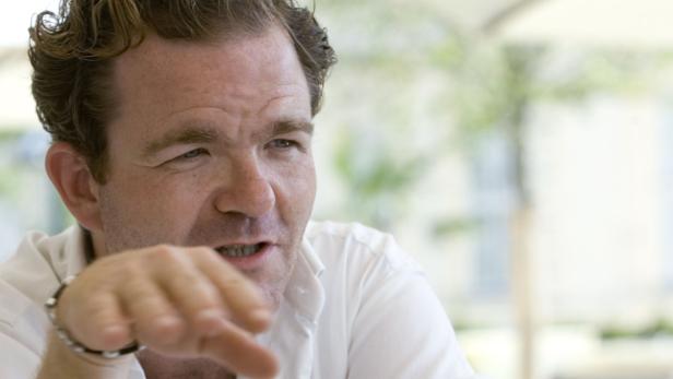 Ein Mann mit hellem Haar gestikuliert und spricht.