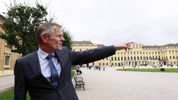 Ein Mann im Anzug zeigt auf Schloss Schönbrunn.