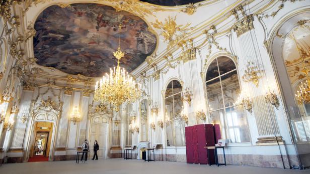 Ein prunkvoller Saal mit goldenen Verzierungen und einem großen Deckengemälde.