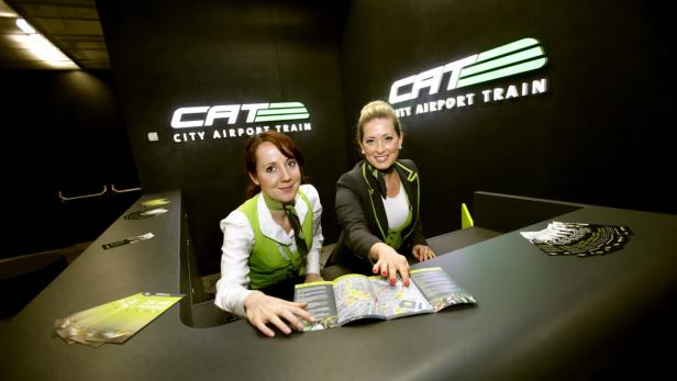 Zwei Mitarbeiterinnen am CAT-Schalter mit Broschüren des City Airport Train.