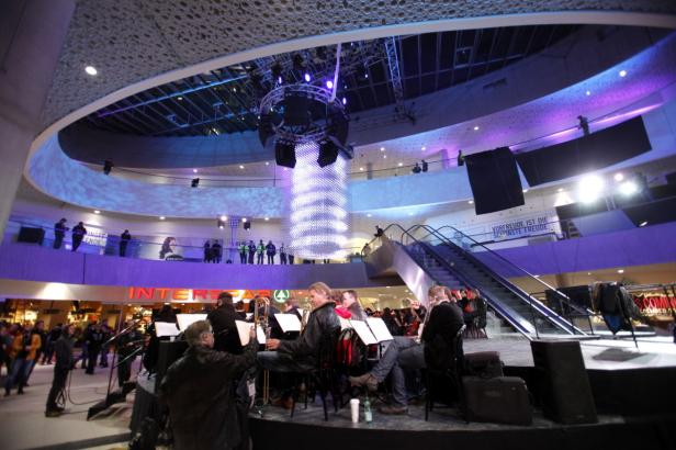 Ein Orchester spielt in einem Einkaufszentrum vor Publikum.
