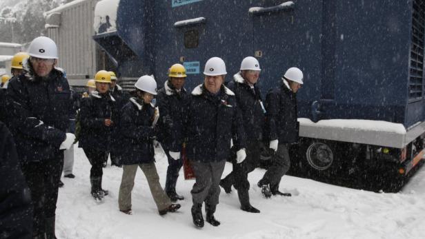 Eine Gruppe von Personen mit Schutzhelmen geht durch den Schnee.