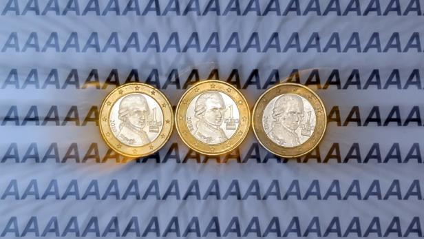 Drei 1-Euro-Münzen liegen auf einem Hintergrund mit dem Buchstaben A.