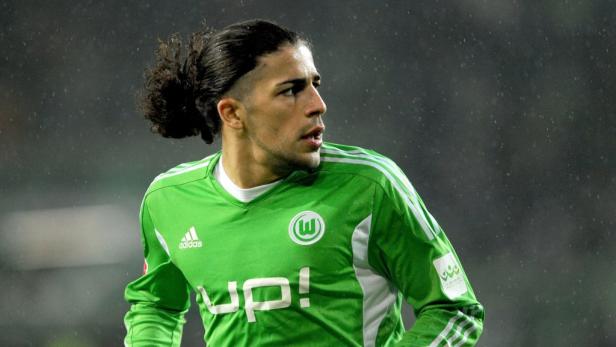 Ein Fußballspieler des VfL Wolfsburg in grünem Trikot blickt zur Seite.