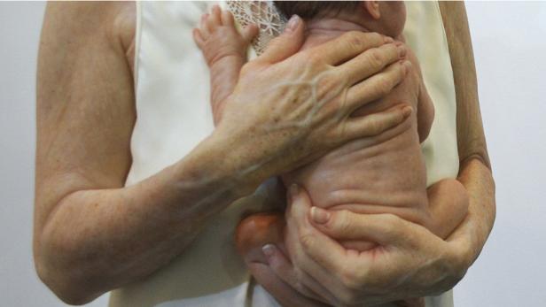 Eine ältere Frau hält ein Neugeborenes im Arm.