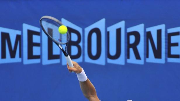 Ein Tennisspieler schlägt einen Ball vor dem Hintergrund des Melbourne-Logos.