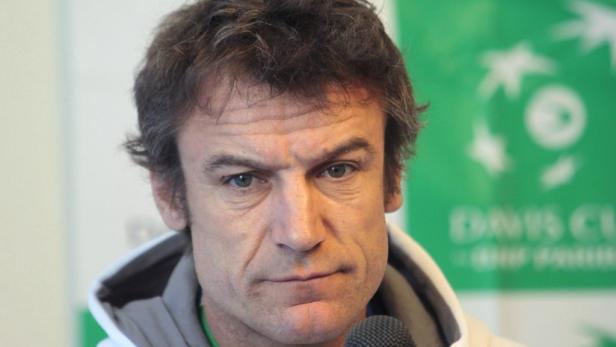 Nahaufnahme eines Mannes vor einem grünen Davis Cup Hintergrund.