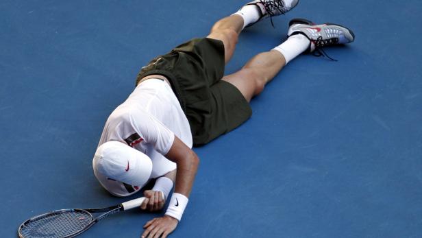 Ein Tennisspieler liegt erschöpft auf dem blauen Platz.