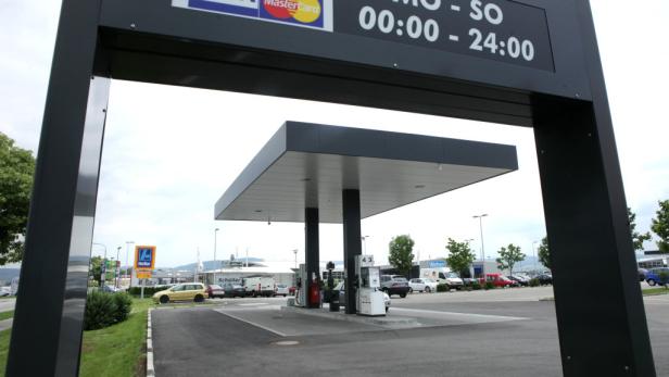 Eine Tankstelle mit einem Schild, das die Öffnungszeiten anzeigt.