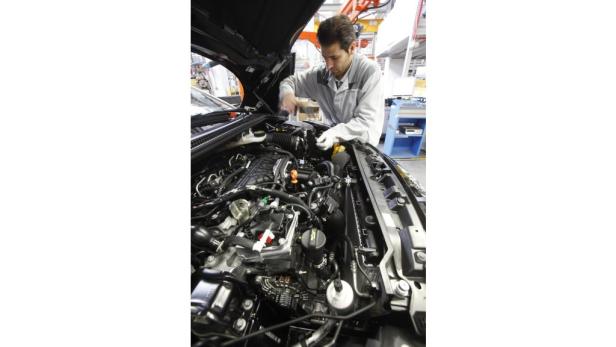 Ein Mechaniker arbeitet an einem Automotor in einer Werkstatt.
