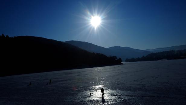 Eine Person und ein Hund stehen auf einem gefrorenen See im Winter.