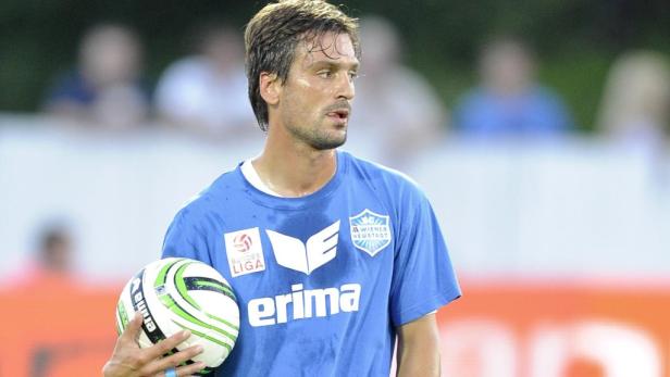 Ein Fußballspieler im blauen Trikot hält einen Ball in der Hand.