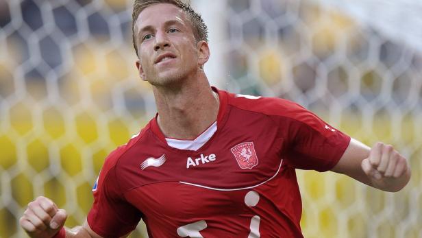 Ein Fußballspieler im roten Trikot von FC Twente jubelt mit geballten Fäusten.