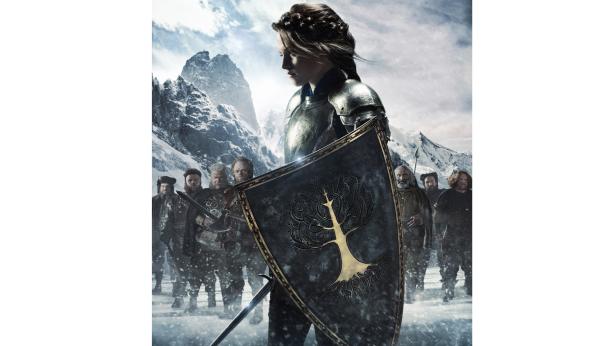 Eine Frau in Rüstung steht mit Schild vor einer Gruppe von Männern in einer verschneiten Berglandschaft.