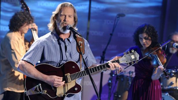 Jeff Bridges spielt Gitarre und singt mit seiner Band auf einer Bühne.