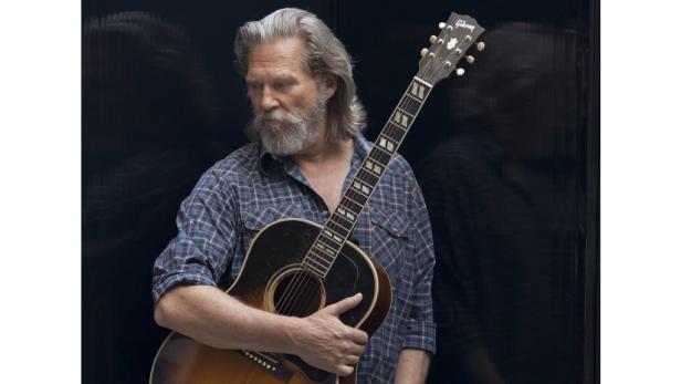 Jeff Bridges hält eine Gitarre der Marke Gibson.