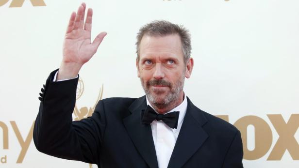 Hugh Laurie winkt auf dem roten Teppich.