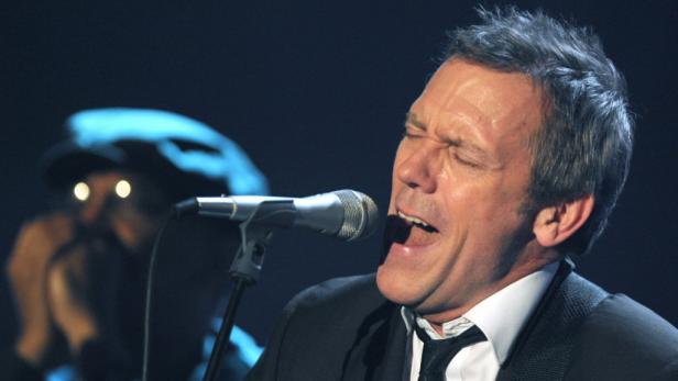 Hugh Laurie singt bei einem Auftritt in ein Mikrofon.