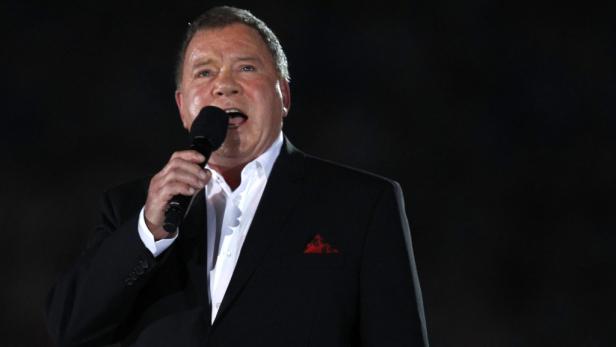 William Shatner singt mit einem Mikrofon in der Hand.