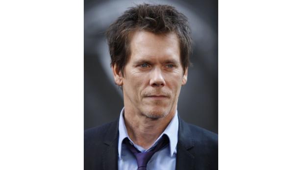 Porträt von Kevin Bacon mit dunklem Anzug und blauem Hemd.