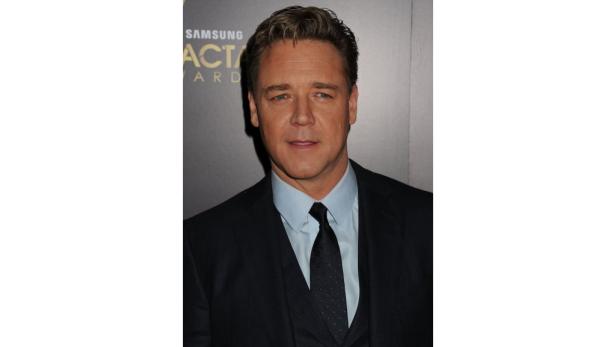 Ein Porträt von Russell Crowe in einem dunklen Anzug und Hemd mit Krawatte.